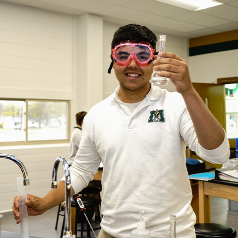 A high school student uses chemistry equipment.